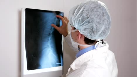 A-young-doctor-examines-the-results-of-a-patient's-X-ray-on-the-wall.-Analyzes-of-the-thorax-and-ribs