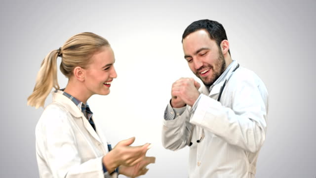 Happy-young-doctors-wearing-white-medical-overall-dancing-on-white-background