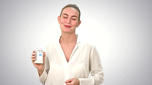 Pretty-woman-describing-and-advertising-pills-for-the-camera-on-white-background