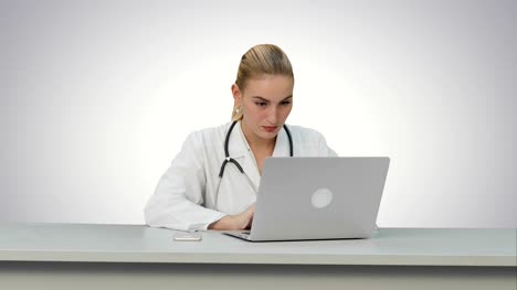 Seriouse-Ärztin-arbeitet-auf-ihrem-Laptop-auf-weißem-Hintergrund