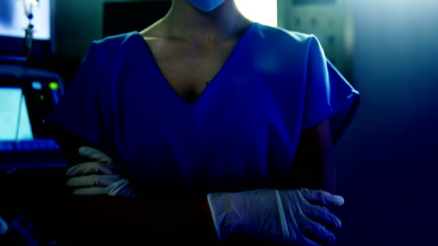 Portrait-of-female-surgeon-standing-with-arms-crossed-in-operating-room