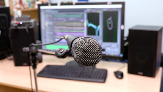 Microphone-on-the-background-of-the-computer-monitor.-Home-recording-Studio.-Close-up.-The-focus-in-the-foreground.-Blurred-background.-Software-for-recording-and-editing-sounds.-4K,-UHD,-Ultra-HD