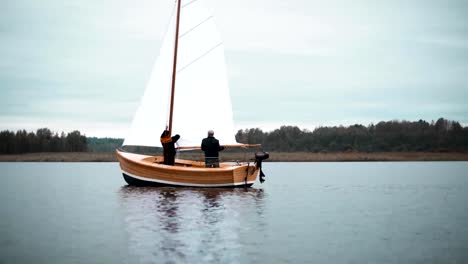 Holz-Segelboot-mit-zwei-Männern,-die-versuchen,-Mast-gesetzt
