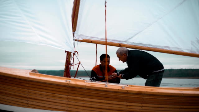 Wood-sailboat-with-two-men-working-with-sail