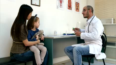 Pediatra-hombre-comprobación-poco-temperatura-de-cabeza-de-niña-con-la-mano-y-dando-su-termómetro
