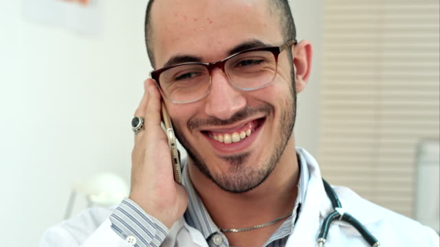 Smiling-doctor-having-a-cheerful-phone-conversation