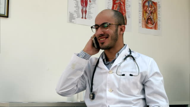 Sonriente-médico-varón-tener-una-conversación-de-teléfono-alegre