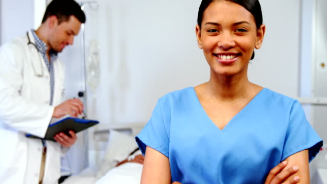Lächelnd-Krankenschwester-stehend-mit-Arme-gekreuzt-im-Krankenhaus