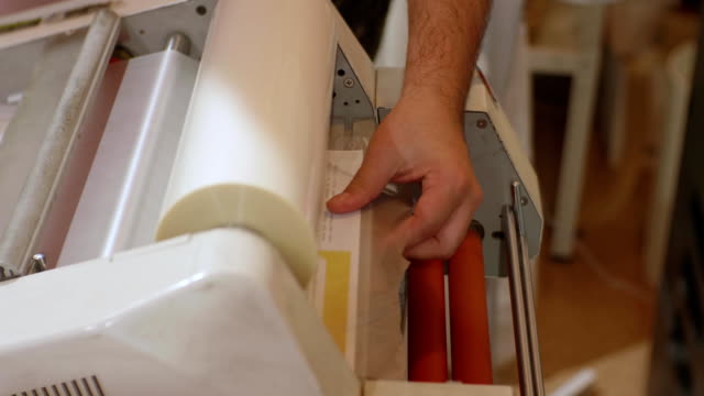 Сaucasian-männlich-arbeiten-mit-Roll-laminator