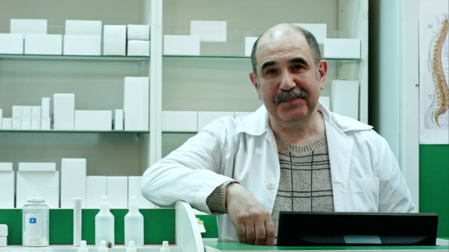 Portrait-of-senior-pharmacist-smiling-and-talking-to-a-camera