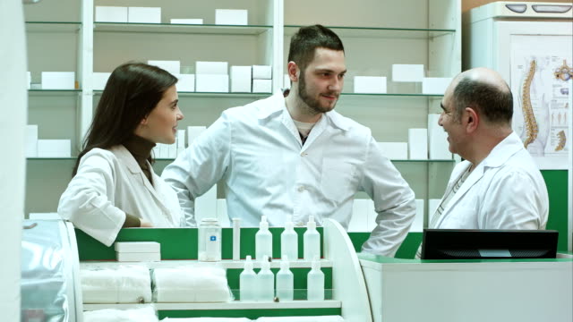 Team-of-pharmacist-chemist-woman-and-man-standing-in-pharmacy-drugstore-and-talking-positive
