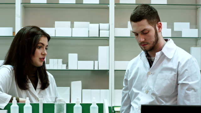 Two-adult-pharmacists-having-conflict,-discussing-problems-at-pharmacy