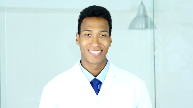 Positiven-lächelnd-entspannen-afro-amerikanischer-Arzt-sitzen-in-Klinik,-Chirurg