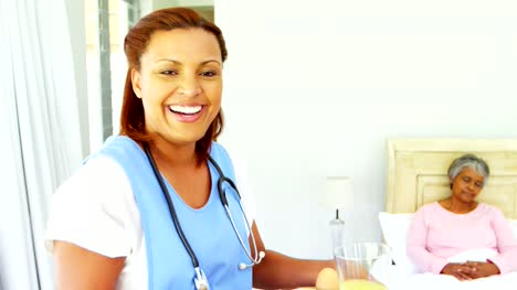 Sonriente-a-médico-femenino-que-sirve-desayunos-a-mujer-senior-en-cama-4k