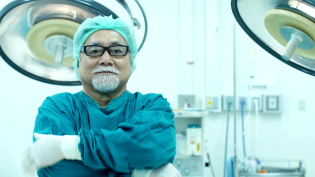 Senior-doctor-looking-to-camera-with-smiling-at-operation-room.-Healthcare-and-Medical-concept.