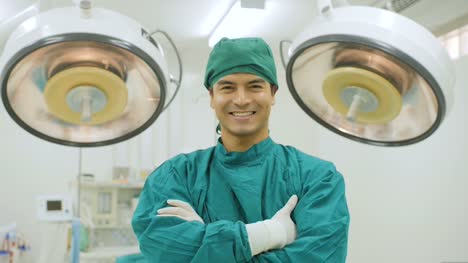 Porträt-des-kaukasischen-männliche-Chirurgen-tragen-volle-chirurgische-scheuert-sich-lächelnd-Kamera-im-Operationssaal-im-Krankenhaus.