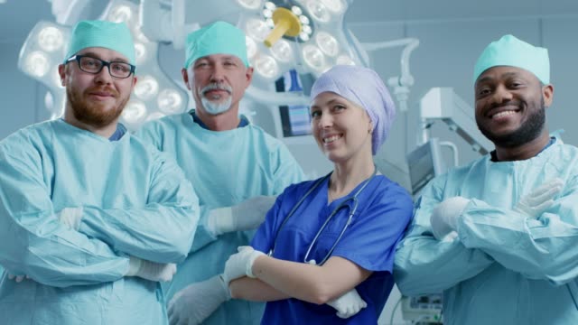 Vielfältigen-Team-Professional-Chirurg,-Assistenten-und-Krankenschwestern-stehen-stolz-mit-gekreuzt-Armen-im-Real-moderne-Krankenhaus-mit-authentischen-Ausrüstung.