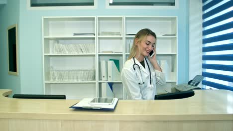 Enfermera-joven-ocupada-usando-la-tableta-y-el-teléfono-en-recepción