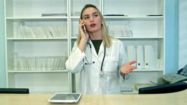 Jung-betonte-Frau-schreien-und-Gestikulieren-beim-sprechen-am-Telefon-an-der-Rezeption-Krankenhaus
