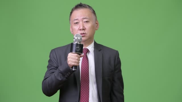 Reife-japanischer-Geschäftsmann-mit-Mikrofon
