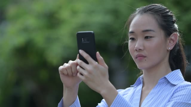 Junge-glücklich-schöne-asiatische-geschäftsfrau-mit-Telefon-im-freien