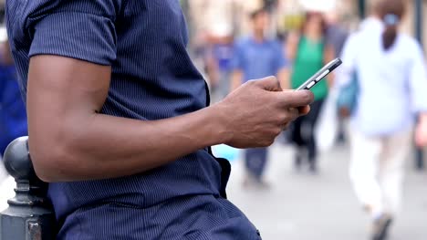 schwarze-amerikanische-Mann-Hände-Tippen-auf-Smartphone-in-der-Stadt