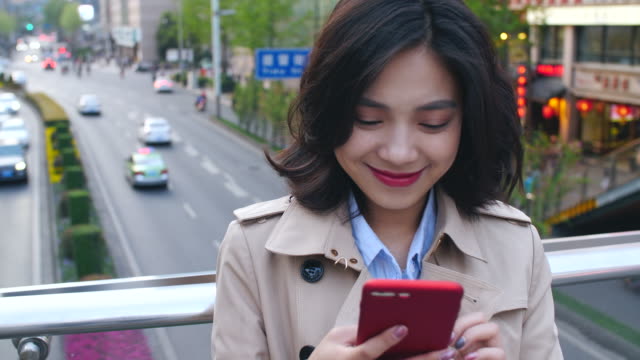 Eine-hübsche-junge-Asiatin-mit-Handy-in-der-Stadt