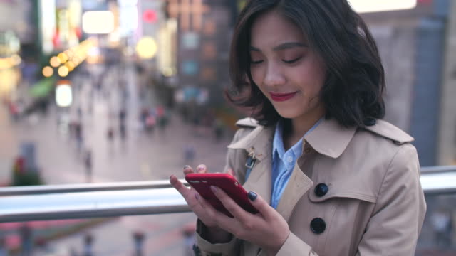 Joven-mujer-asiática-usando-teléfono-inteligente-en-la-ciudad