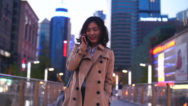 Pretty-happy-young-asian-woman-talking-on-the-mobile-phone-while-walking-in-the-street-in-slow-motion