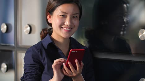 Jóvenes-asiáticos-empresaria-mirando-su-teléfono-móvil-por-el-vidrio-de-ventana-de-la-oficina,-lenta-4k