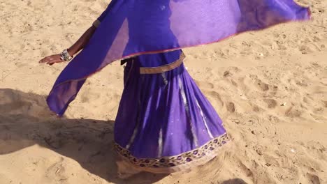 Frau-trägt-traditionelle-blau-Kleid-und-Schal,-tanzen-und-wirbeln-im-Wüstensand-von-Rajasthan