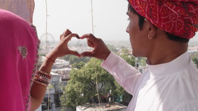 Rajasthani-couple-making-a-heart-sign-with-their-hands-overseeing-the-Pushkar-Mela-festival-in-Rajasthan,-India