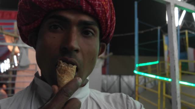 Indian-man-eating-ice-cream-and-looking-at-the-Pushkar-Mela-carnival-festival-in-Rajasthan