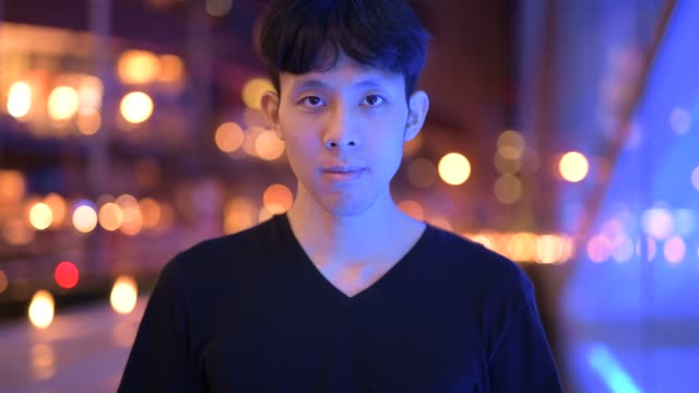 Porträt-von-asiatischer-Mann-lächelnd-im-Freien-bei-Nacht