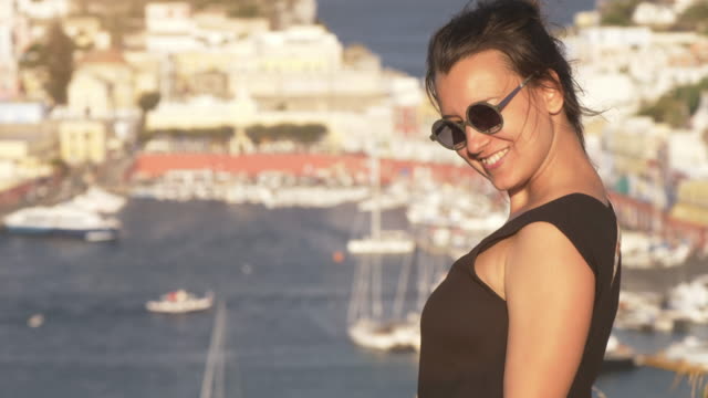 Glückliche-junge-Frau-zeigenden-Touristenort-auf-der-Insel-Ponza-in-Italien-traditionell-Meer-Stadtlandschaft