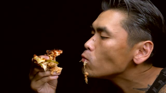 Slow-Motion-asiatischen-tätowierter-Mann-isst-leidenschaftlich-gern-ein-Stück-pizza