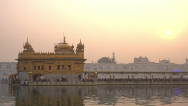Video-of-Sikh-pilgrims-in-the-Golden-Temple-at-sunset-during-celebration-day-in-December-in-Amritsar,-Punjab,-India.-Harmandir-Sahib-is-the-holiest-pilgrim-site-for-the-Sikhs.