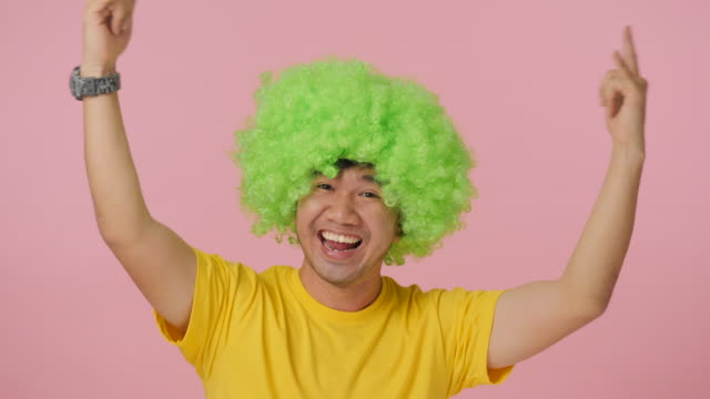Young-crazy-man-with-colored-afro-wig-expressing-happiness-on-pink-background.