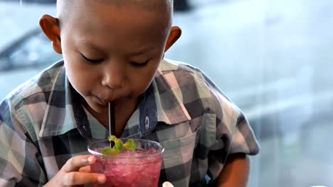 Lindo-niño-asiáticos-disfrutan-de-beber-jugo-en-el-restaurante.-Video-Slow-motion