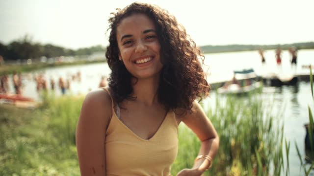 Portrait-of-young-woman-near-a-lake,-smiling.