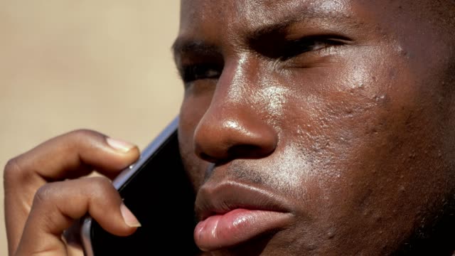 close-up-on-Youn-black-business-african-man-talking-by-phone--outdoor