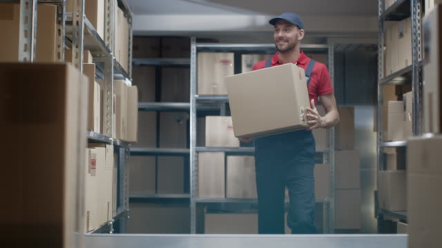 Trabajador-almacén-entra-en-almacén-con-una-caja-de-cartón-y-pone-en-un-estante.
