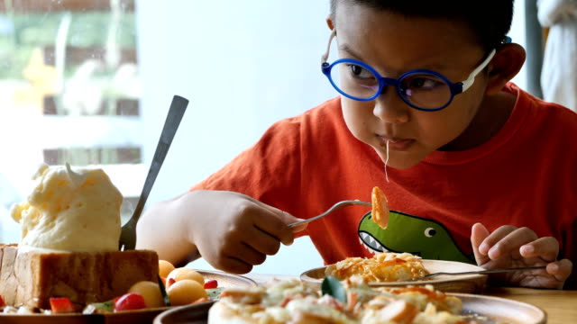 Süße-asiatische-Kinder-halten-in-Gabel-und-Messer-schneidet-die-essende-Pizza-im-restaurant