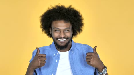 Afro-amerikanischer-Mann-gestikulieren-Daumen-oben-auf-gelbem-Hintergrund