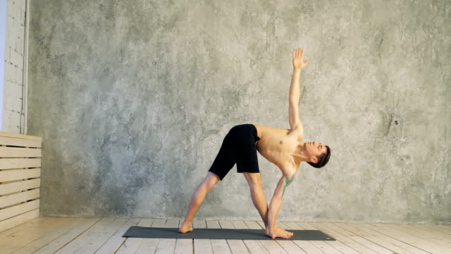 Yoga-posición-asana-vida-sana-ejercicio-concepto---hombre-haciendo-Ashtanga-Vinyasa-yoga-asana-Parivrtta-trikonasana---triángulo-revolución-plantean-indores