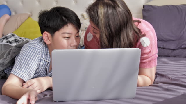 Familia-feliz-madre-e-hijo-viendo-en-el-ordenador-portátil-con-cara-de-sonrisa,-lento-Asia-resto-familia-movimiento-4K-en-la-cama-con-el-ordenador-portátil