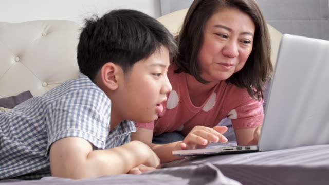 Familia-feliz-madre-e-hijo-viendo-en-el-ordenador-portátil-con-cara-de-sonrisa,-lento-Asia-resto-familia-movimiento-4K-en-la-cama-con-el-ordenador-portátil