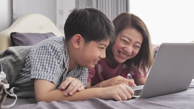Glückliche-Familie-Mutter-und-Sohn-gerade-auf-Laptop-Computer-mit-Lächeln-Gesicht,-Slow-Motion-4K-asiatischen-Familie-Rest-auf-Bett-mit-Laptop-computer