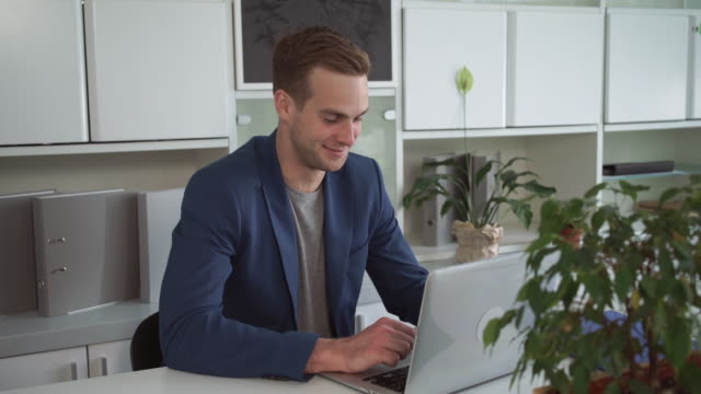 Hombre-de-negocios-feliz-trabajando-en-la-computadora-portátil-en-la-oficina-moderna