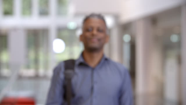 Middle-aged-black-male-teacher-walking-into-focus-in-a-lobby